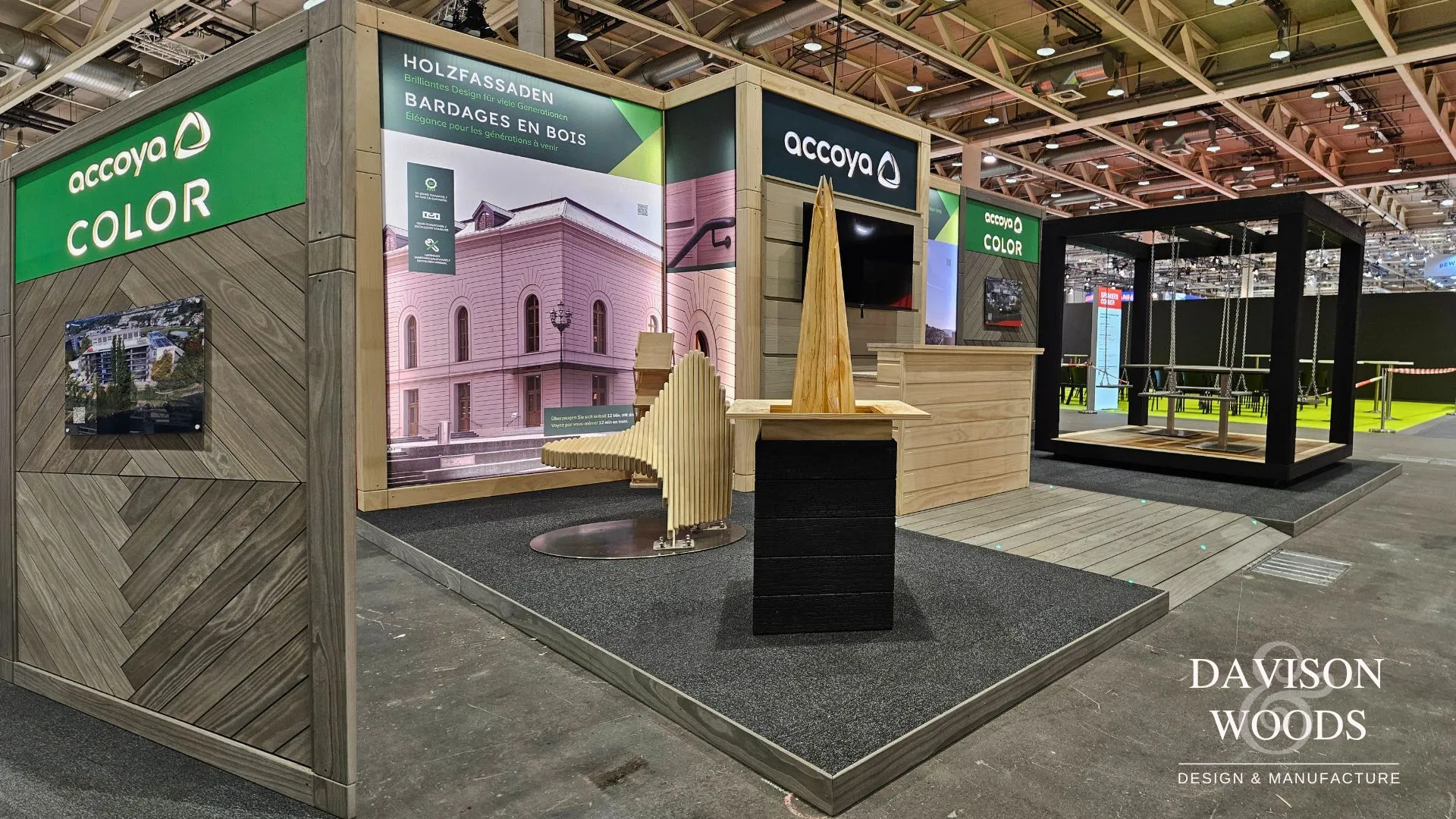 A diamond pattern wall made of Accoya Color Grey planks stands next to a wall with large wall graphics stating Accoya Color