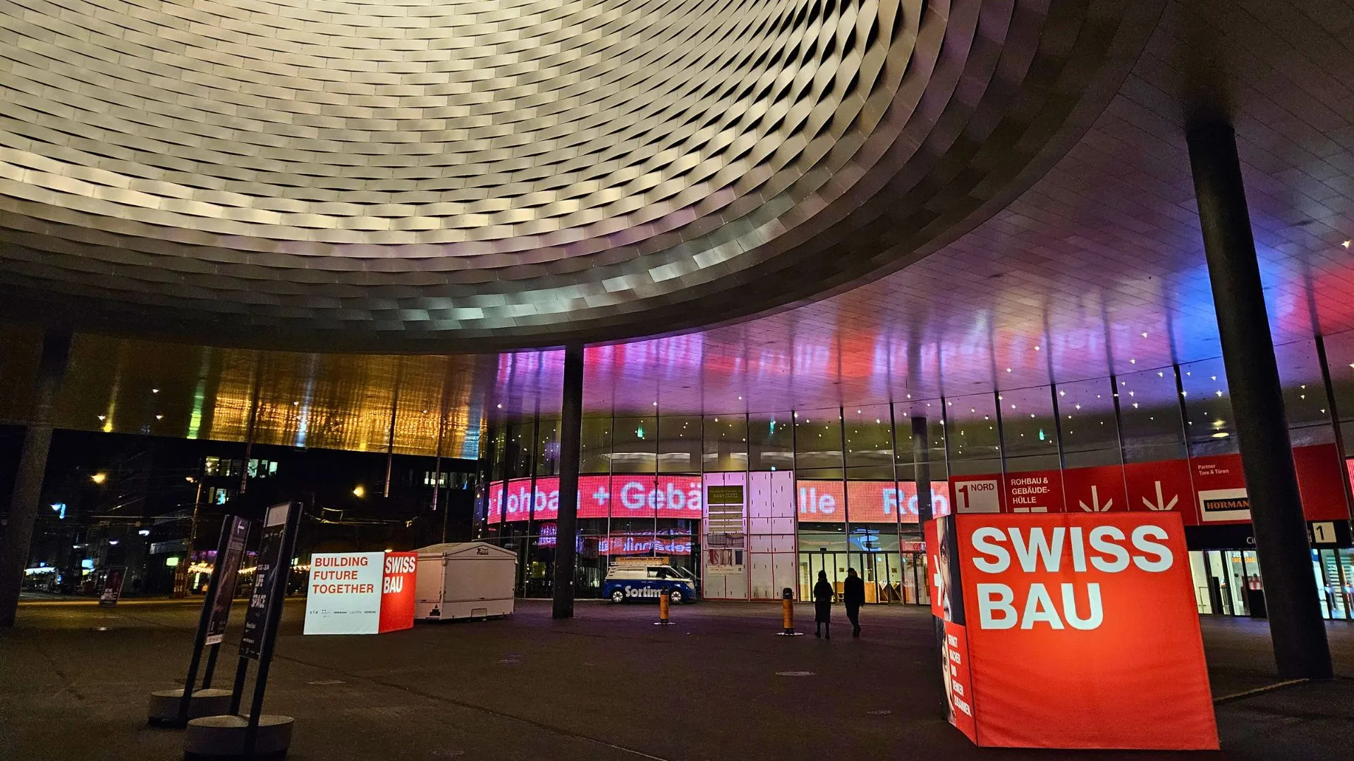 A large red cube with white letters 'SWISSBAU' sits proud at the entrance to the Swissbau 2024 exhibition hall